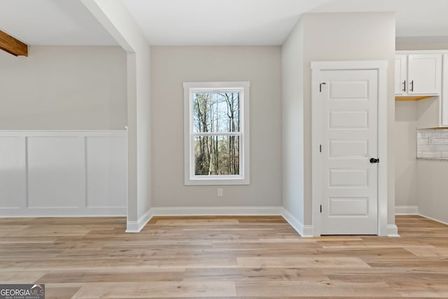 entryway with light wood-style floors and a wainscoted wall