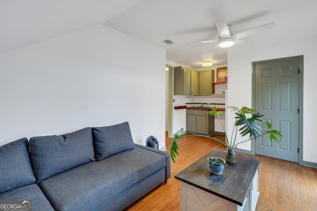 living room featuring lofted ceiling, ceiling fan, and light hardwood / wood-style flooring