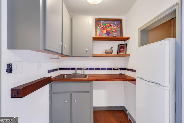 kitchen featuring white fridge, light hardwood / wood-style flooring, sink, and gray cabinets