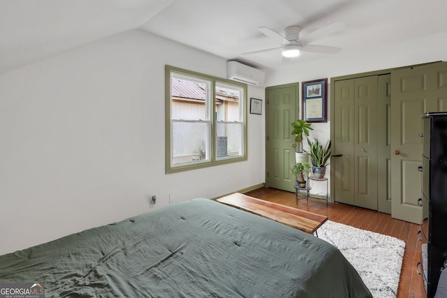 bedroom featuring light hardwood / wood-style flooring, ceiling fan, vaulted ceiling, and a wall mounted AC