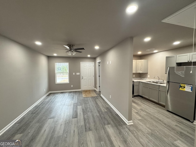 kitchen featuring stainless steel refrigerator, light hardwood / wood-style floors, sink, and gray cabinetry