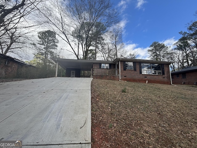 view of front of house with brick siding, driveway, crawl space, a carport, and a front yard