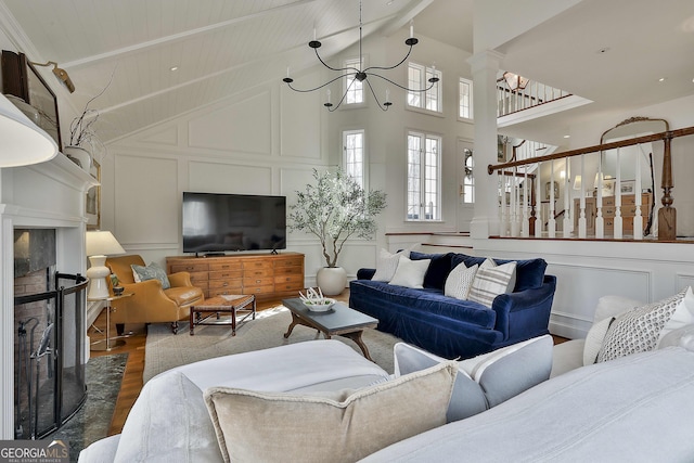 living room featuring decorative columns, dark wood-type flooring, a fireplace, high vaulted ceiling, and beam ceiling