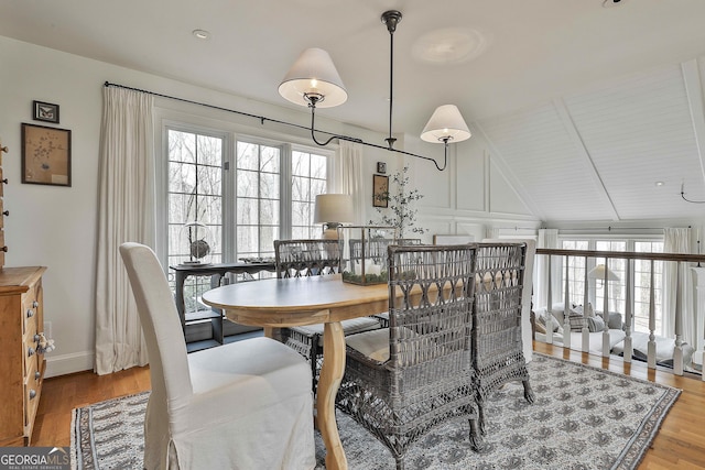 dining area featuring hardwood / wood-style flooring, vaulted ceiling, and a wealth of natural light