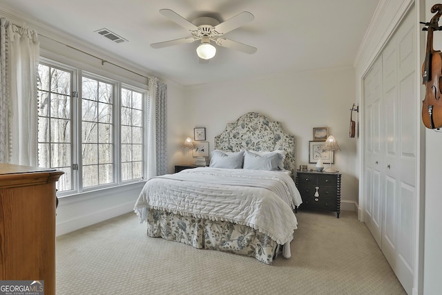 carpeted bedroom with ornamental molding, a closet, and ceiling fan