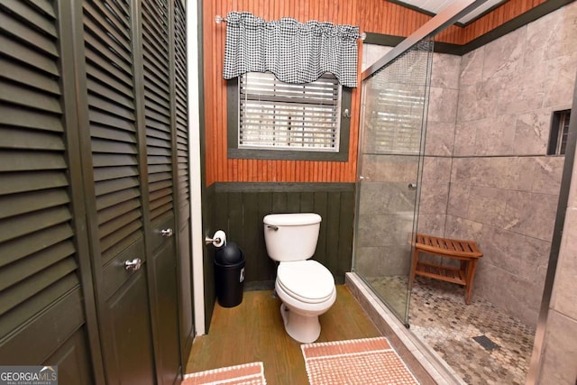 bathroom featuring toilet, an enclosed shower, and wood-type flooring