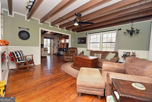 living room featuring beam ceiling, ceiling fan with notable chandelier, and hardwood / wood-style flooring