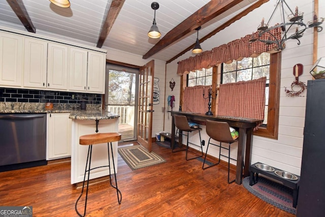 kitchen with a kitchen breakfast bar, dishwasher, pendant lighting, white cabinetry, and dark stone countertops