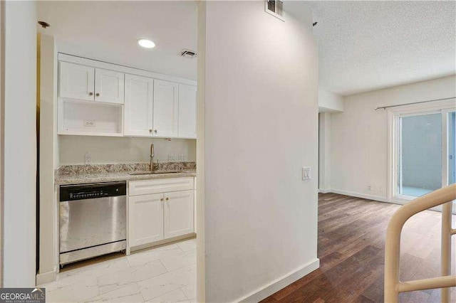 kitchen with light stone countertops, a textured ceiling, white cabinets, stainless steel dishwasher, and sink