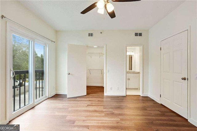 unfurnished bedroom featuring access to outside, ensuite bath, light hardwood / wood-style floors, a closet, and a spacious closet