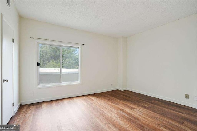 empty room with a textured ceiling and wood-type flooring