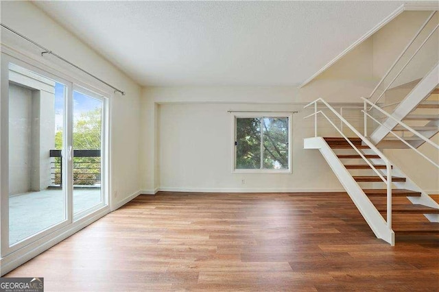 unfurnished living room with a healthy amount of sunlight, a textured ceiling, and hardwood / wood-style floors