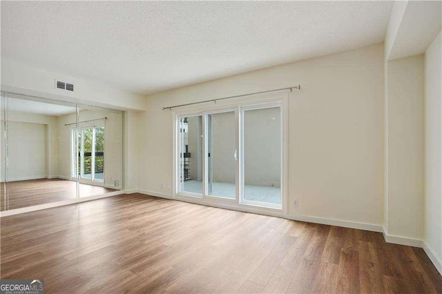 unfurnished living room with a textured ceiling and hardwood / wood-style flooring