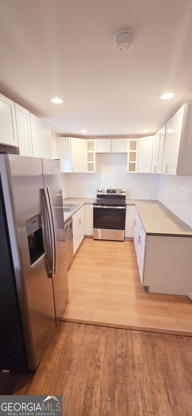 kitchen with appliances with stainless steel finishes, light wood-type flooring, and white cabinets