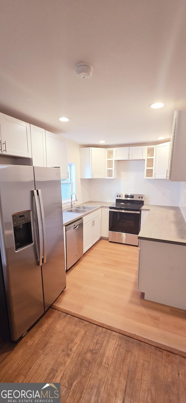 kitchen with white cabinetry, appliances with stainless steel finishes, sink, and light hardwood / wood-style floors