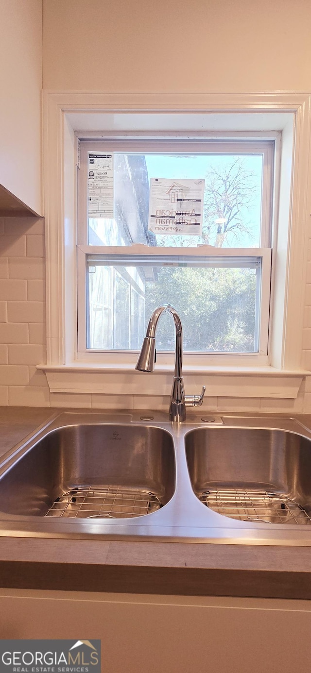 interior details with white cabinetry, sink, and tasteful backsplash