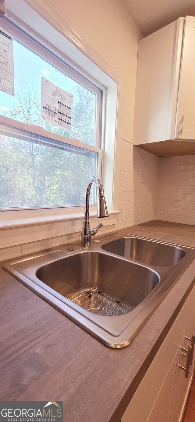 kitchen with sink, white cabinets, and backsplash