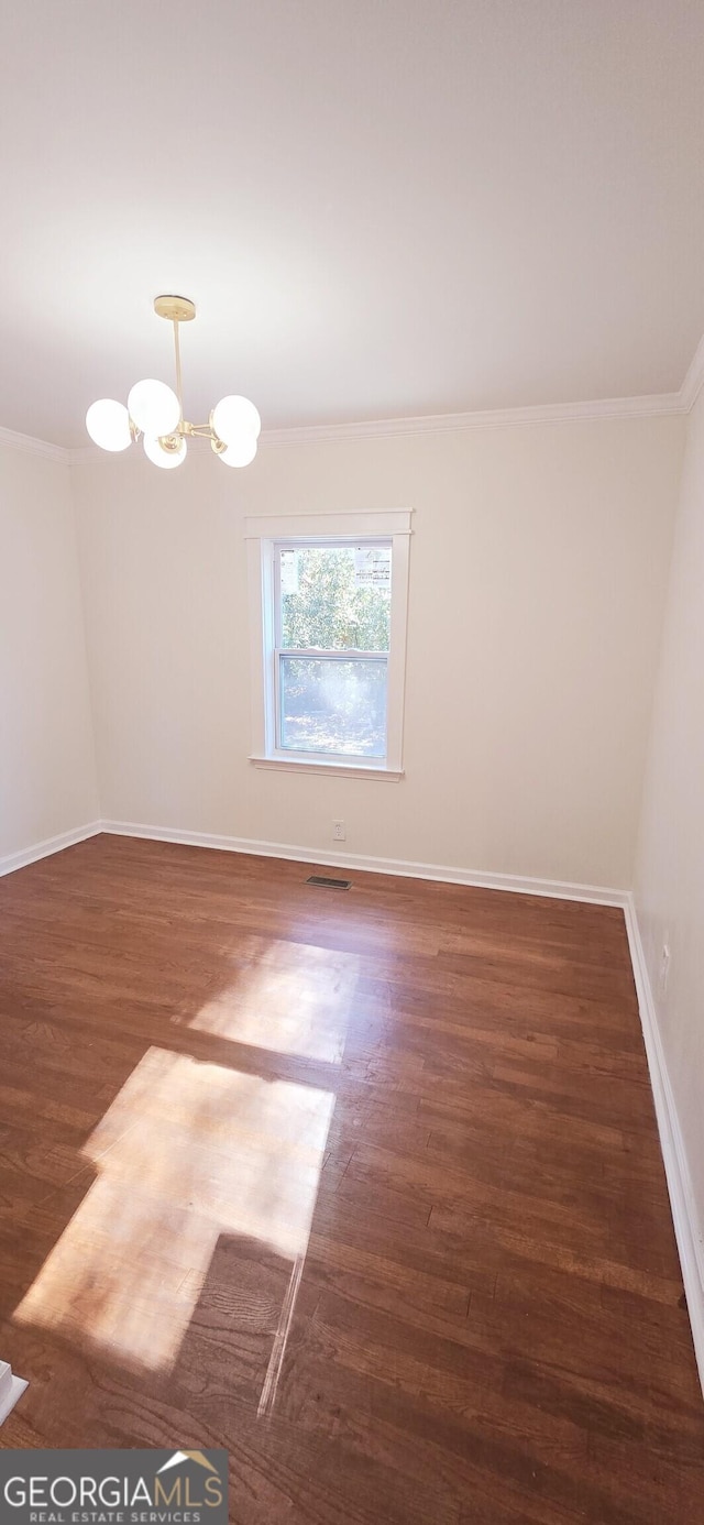 empty room featuring a chandelier, crown molding, and dark hardwood / wood-style floors