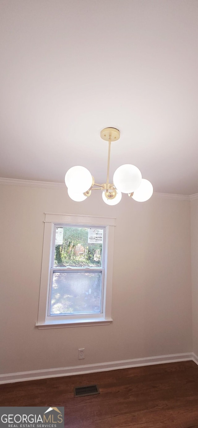 unfurnished room featuring a chandelier, dark hardwood / wood-style floors, and ornamental molding