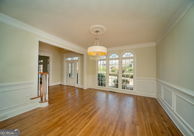 unfurnished dining area with a chandelier, crown molding, and hardwood / wood-style flooring