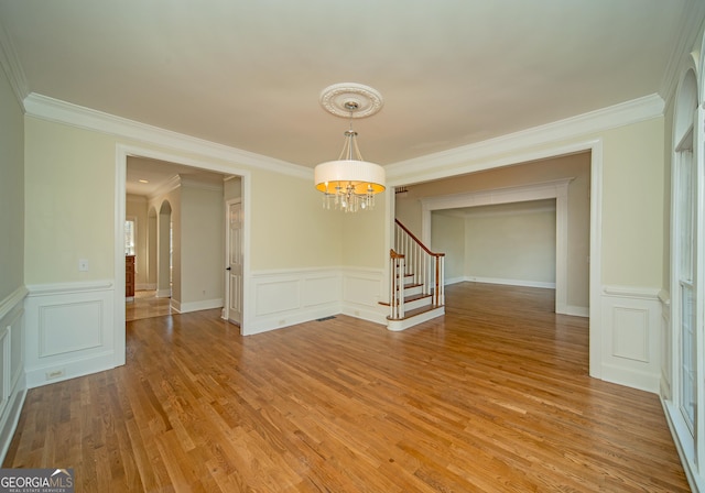 unfurnished room featuring crown molding, an inviting chandelier, and wood-type flooring