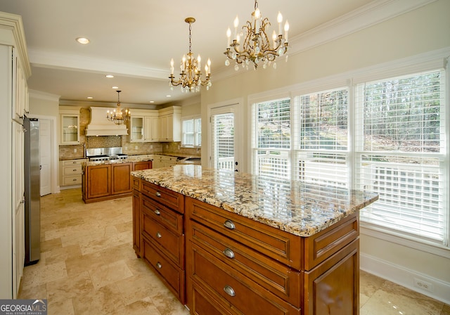 kitchen with a center island, decorative light fixtures, an inviting chandelier, custom range hood, and decorative backsplash