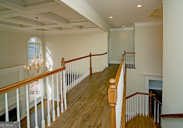 hall featuring beam ceiling, an inviting chandelier, ornamental molding, coffered ceiling, and hardwood / wood-style floors