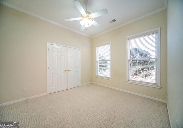 unfurnished bedroom featuring light colored carpet, a closet, ceiling fan, and ornamental molding