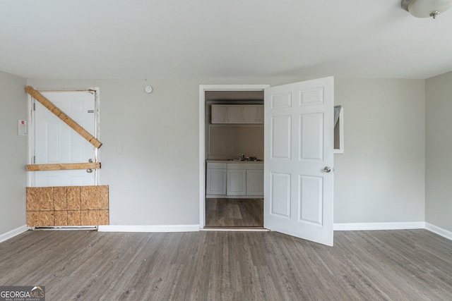 unfurnished bedroom featuring a sink, baseboards, and wood finished floors