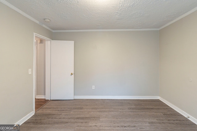 empty room with a textured ceiling, baseboards, wood finished floors, and ornamental molding