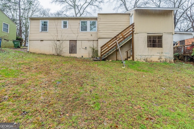 rear view of house with a lawn and stairs