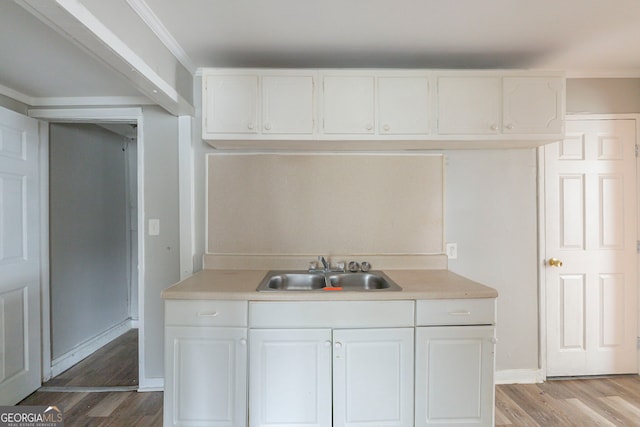 kitchen with light countertops, a sink, light wood-style flooring, and white cabinets