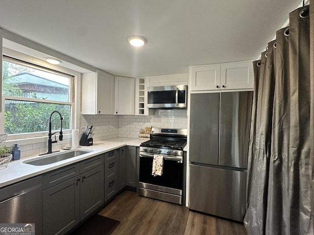 kitchen with a sink, gray cabinets, dark wood-type flooring, appliances with stainless steel finishes, and white cabinets