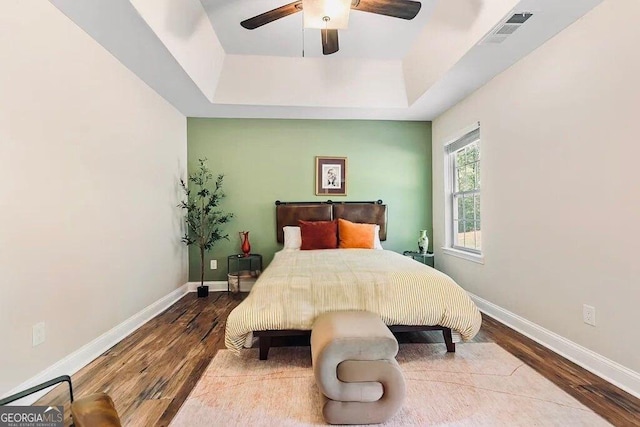 bedroom with a tray ceiling, hardwood / wood-style flooring, and ceiling fan