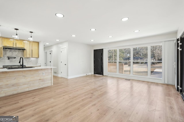 kitchen featuring light wood-style floors, a sink, backsplash, and light brown cabinetry