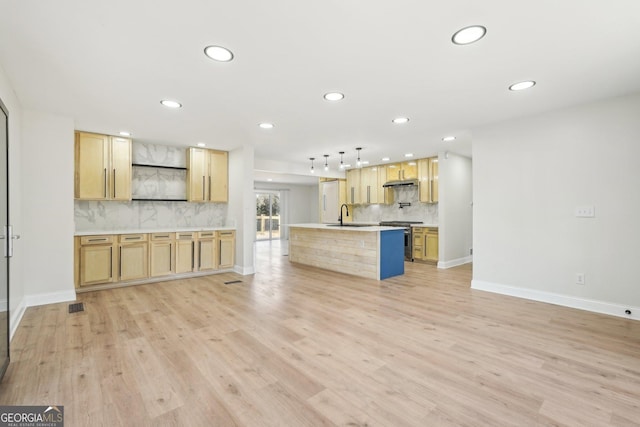 unfurnished living room featuring light wood-style floors, baseboards, a sink, and recessed lighting