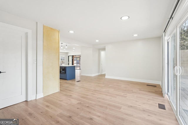 unfurnished living room with light wood-type flooring, baseboards, visible vents, and recessed lighting