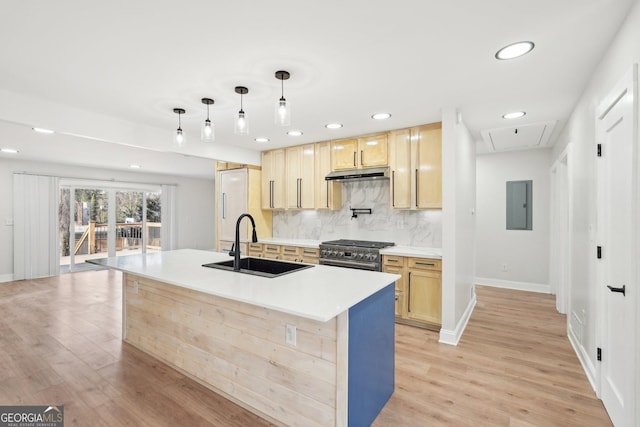 kitchen featuring decorative light fixtures, light countertops, a sink, high end stove, and under cabinet range hood