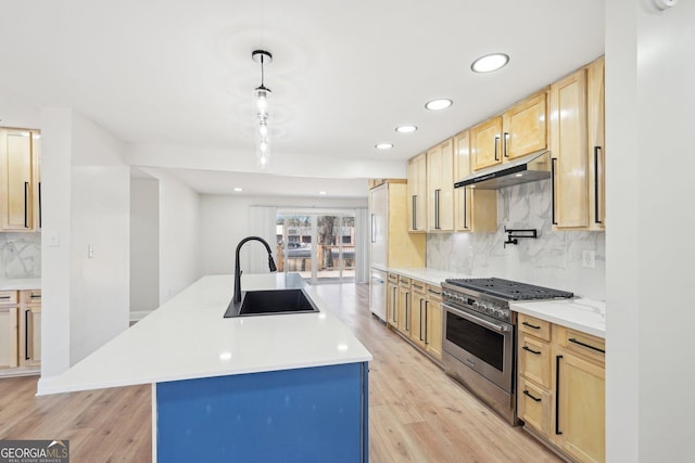 kitchen featuring decorative light fixtures, a sink, light countertops, high end range, and a center island with sink