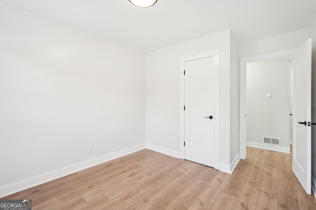 empty room with baseboards, visible vents, and light wood finished floors