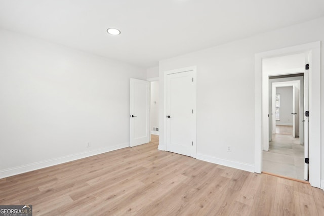 unfurnished bedroom featuring a closet, recessed lighting, light wood-style flooring, and baseboards