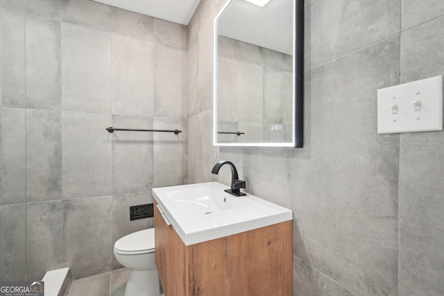 bathroom featuring tile walls, vanity, and toilet