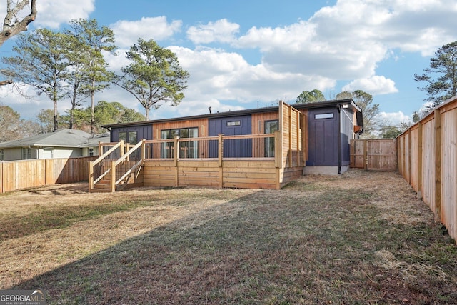 rear view of house featuring a fenced backyard, a yard, and stairs