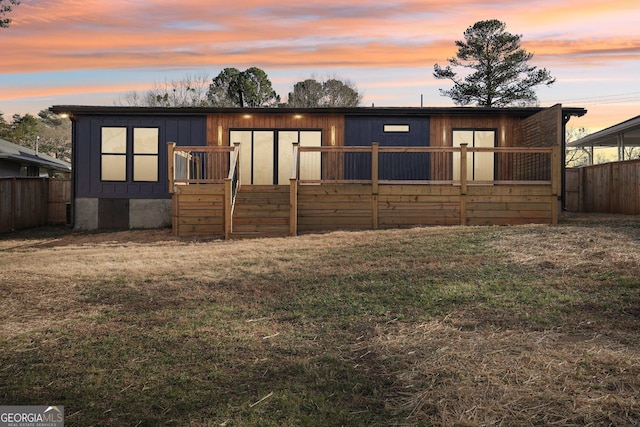 back of property at dusk with a yard and fence