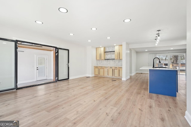 unfurnished living room featuring baseboards, a sink, light wood-style flooring, and recessed lighting