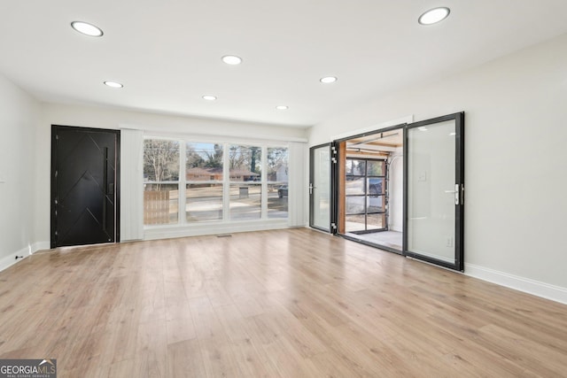 unfurnished room featuring light wood finished floors, baseboards, and recessed lighting