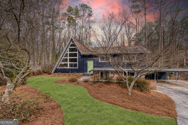 view of front facade featuring driveway, an attached carport, and a front yard