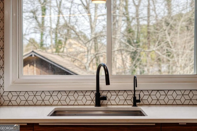 interior details featuring tasteful backsplash, light countertops, and a sink