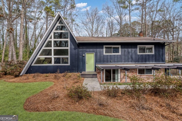 view of front of property with a front yard, board and batten siding, and brick siding