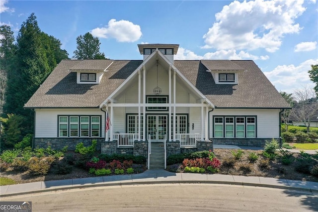 craftsman house with stone siding, covered porch, and a shingled roof